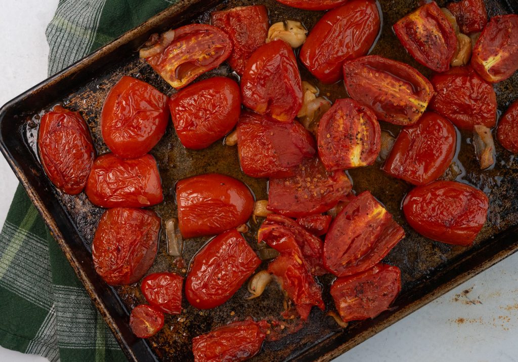 roasted tomatoes with garlic and shallots on a sheet pan