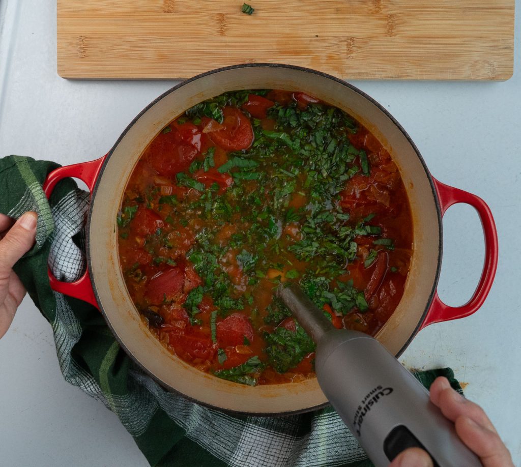 using immersion blender to blend soup until it is completely incorporated and all one texture