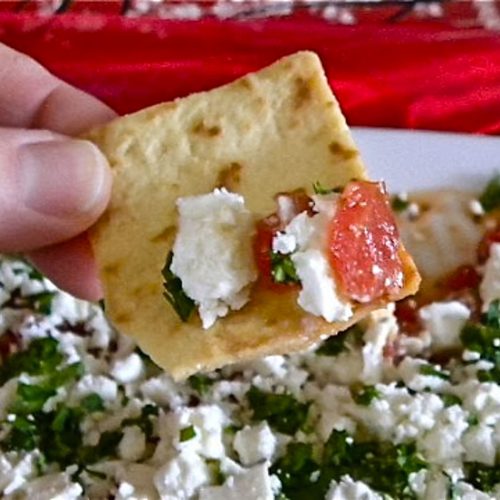 Dipping pita chip into festive feta dip.