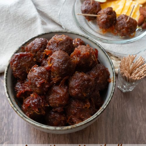 bowl of appetizer meatballs, with toothpicks off to the right, plate small plate with selection of appetizers on it in the back ground