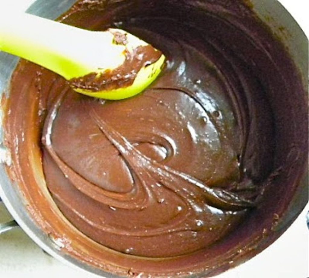 no bake cookie fudge in a saucepan being stirred with a green spatula