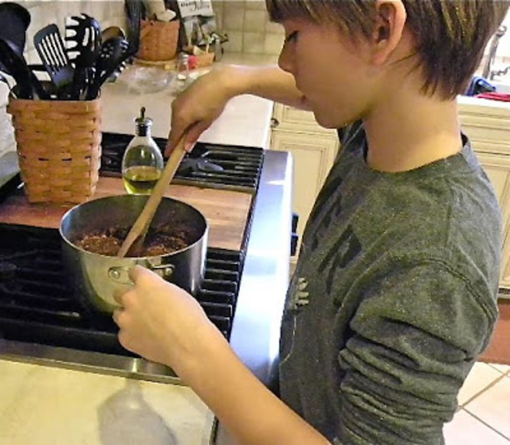 boy at stove stirring no bake cookies in saucepan