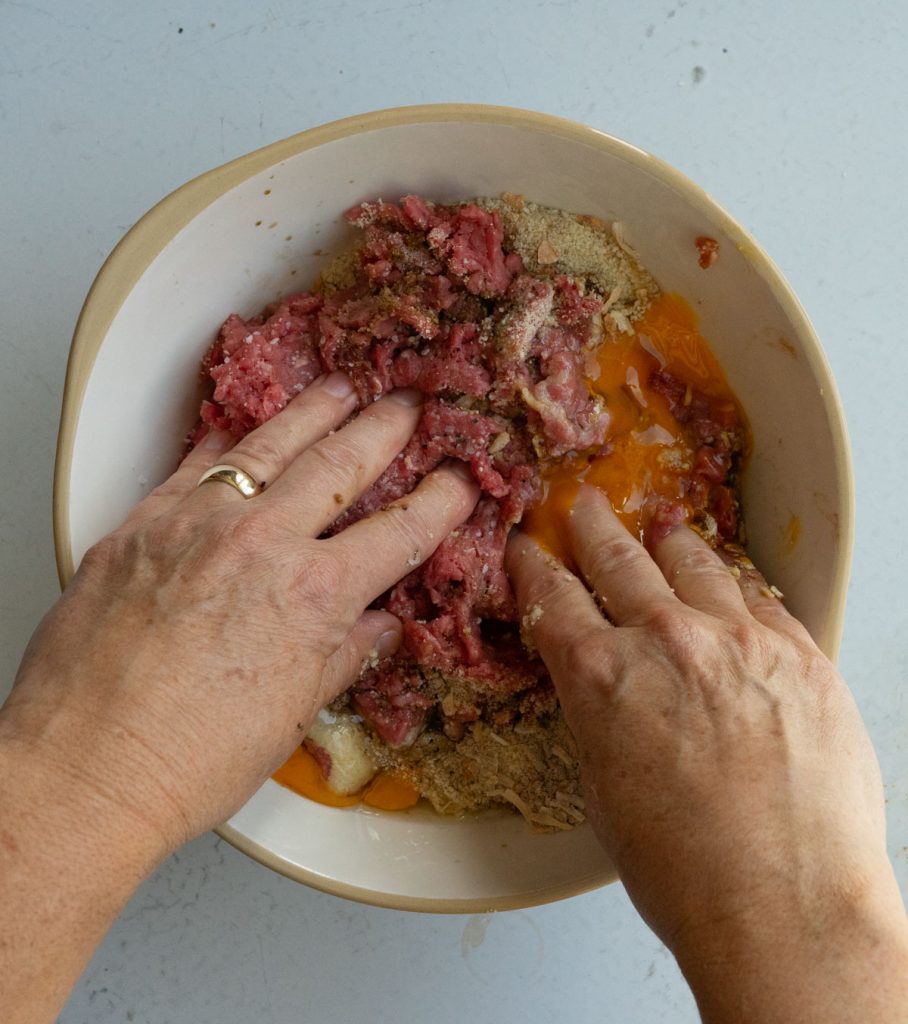 hands mixing meatball ingredients together