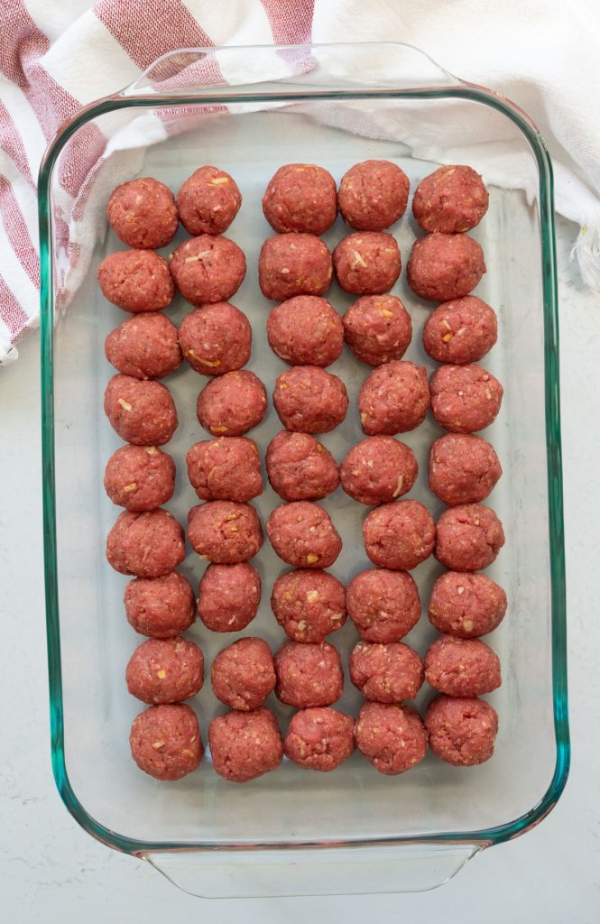 glass baking dish lined with unbaked meatballs