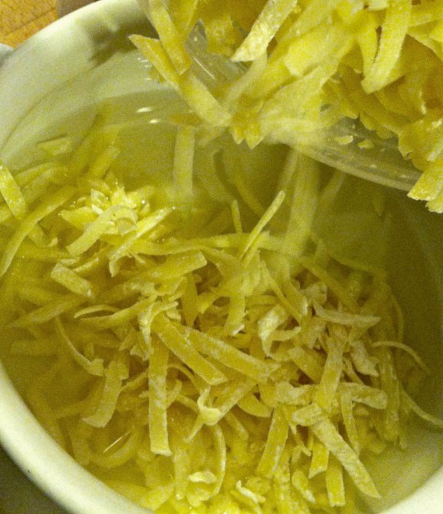 Adding shredded cheese to the warm wine in the fondue pot