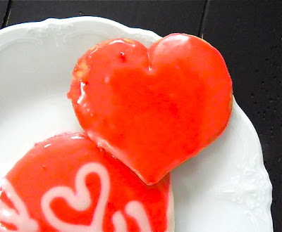 heart shaped sugar cookies with red icing on a white plate