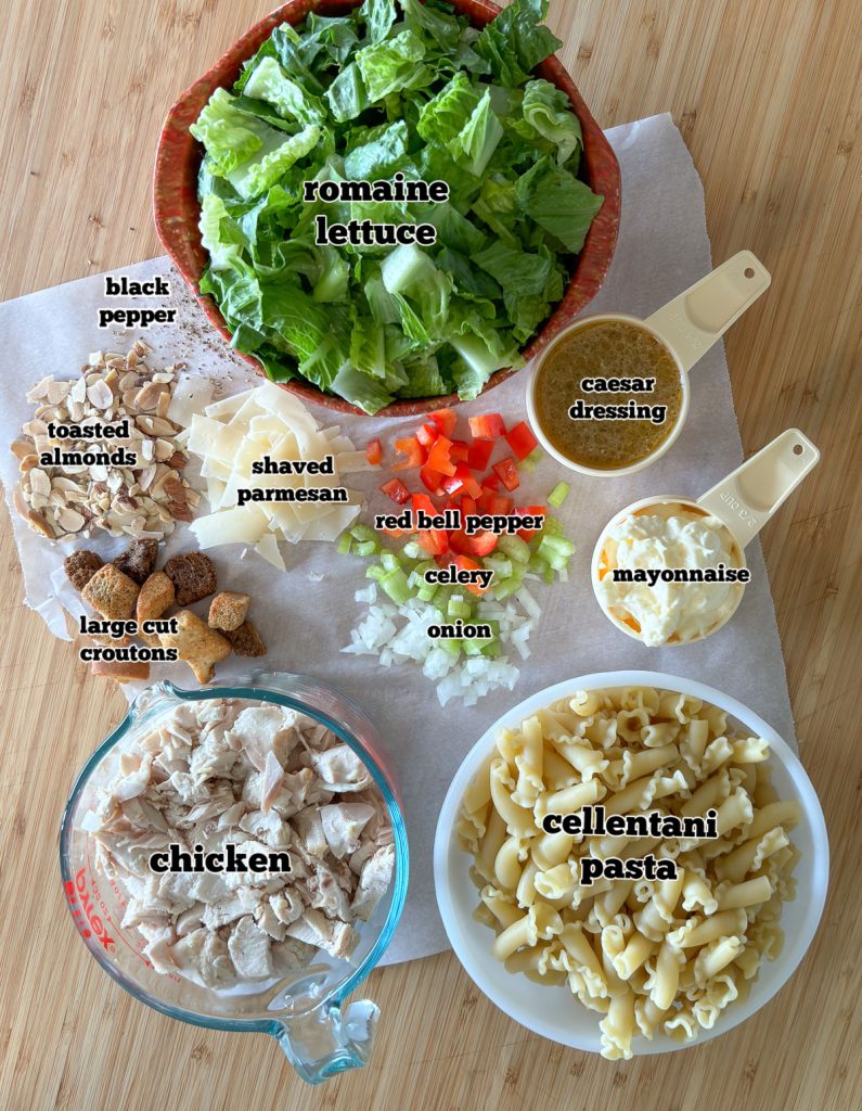 ingredient photo for chicken caesar pasta salad on parchment paper on wood cutting board