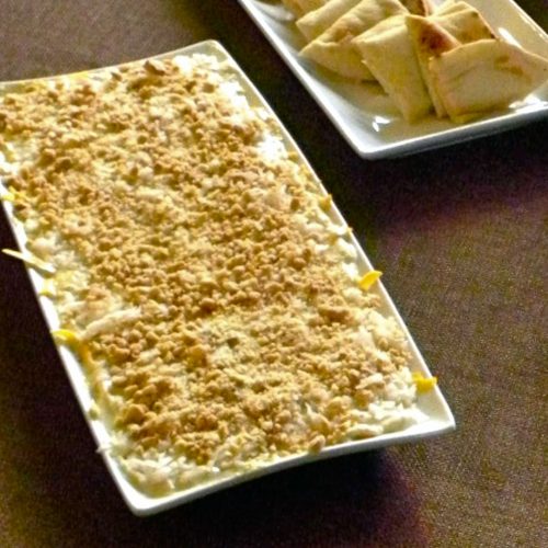 indian dip on a white platter with naan bread wedges on a table with a brown table cloth