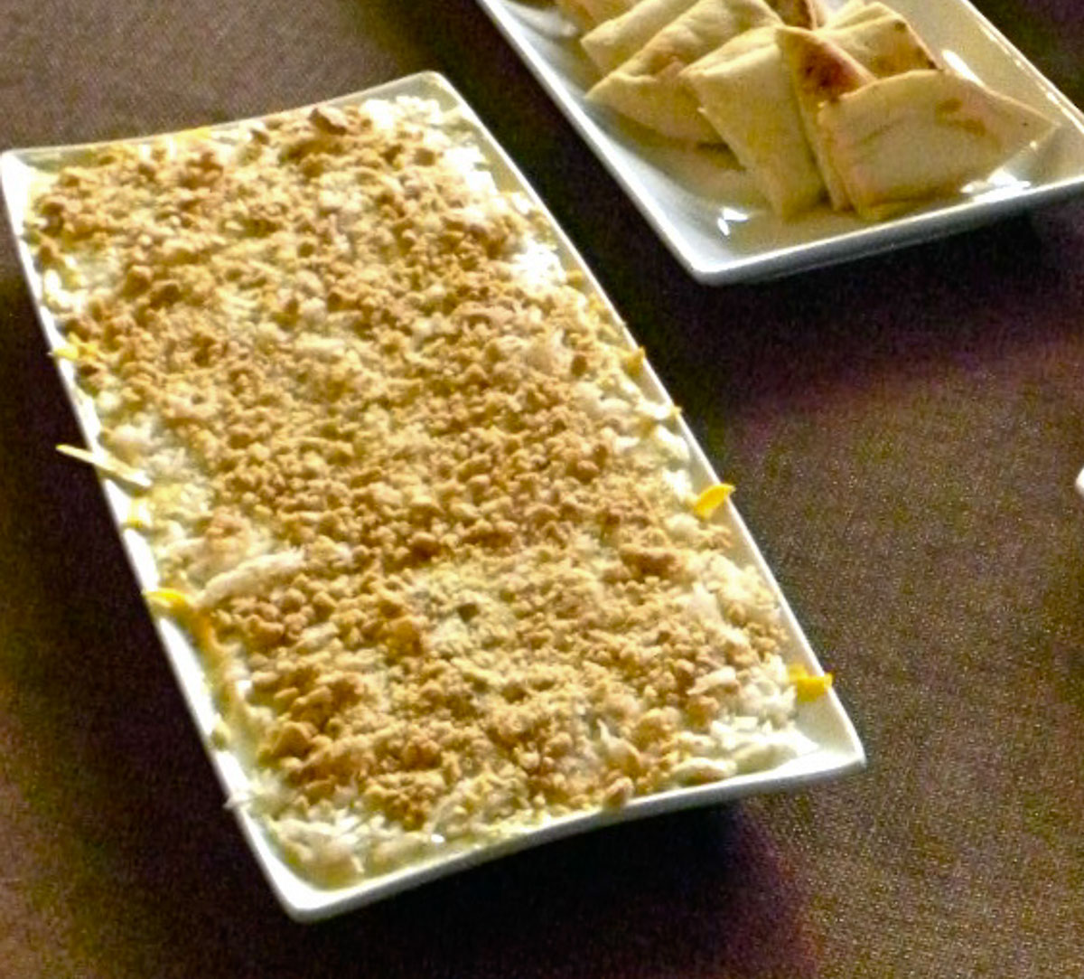 indian dip on a white platter with naan bread wedges on a table with a brown table cloth