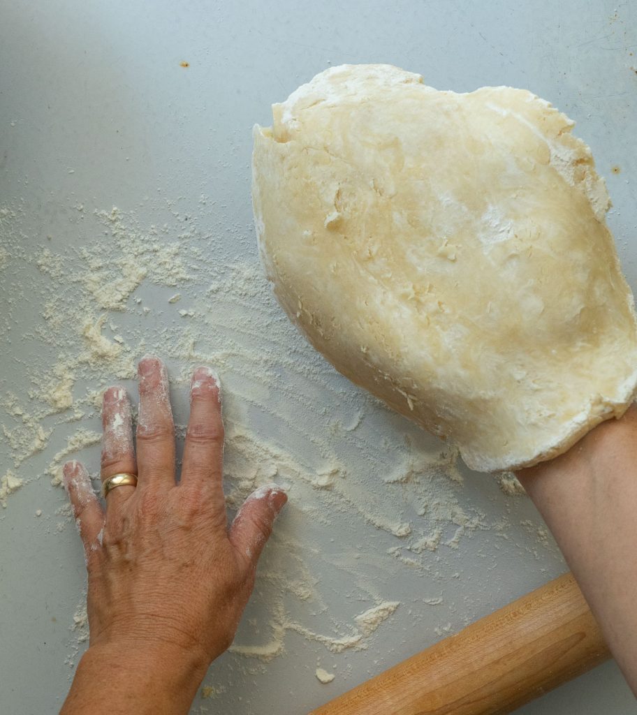 lifting pie crust up and dusting countertop with flour