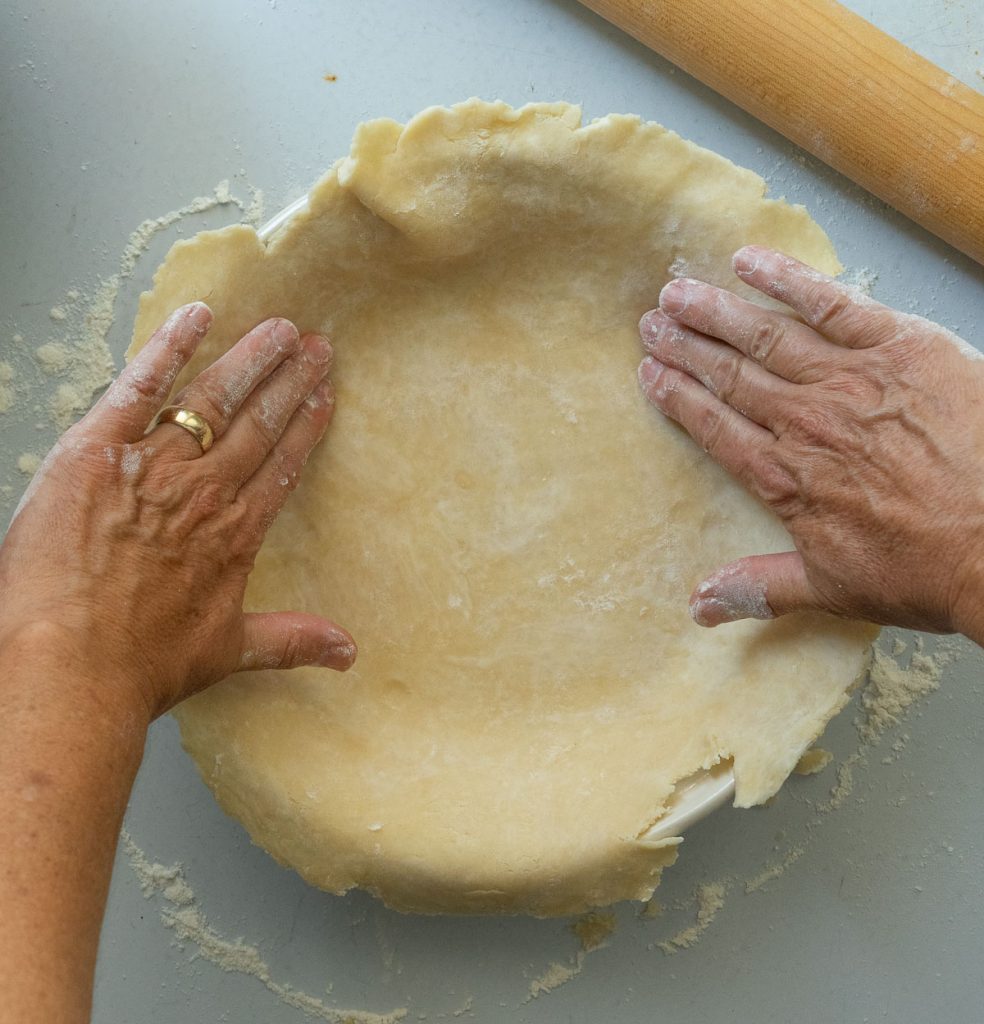 pressing pie crust into pie dish 