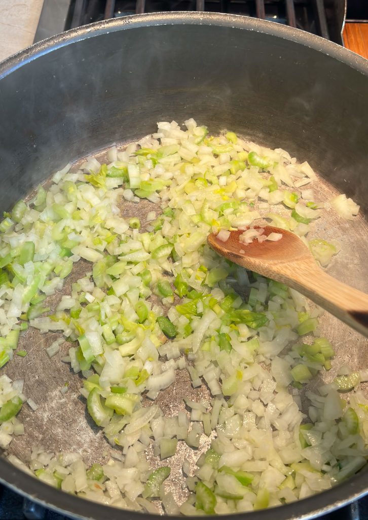 onions and celery being sauted in large pot on stove top