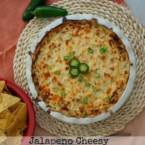 white round dish of jalapeno cheesy chicken dip on a rattan place mat with a bowl of tortilla chips in upper right corner