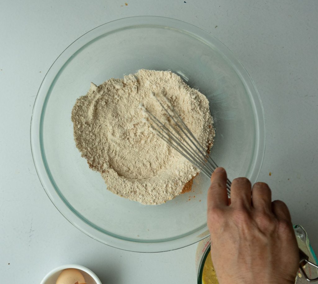 flour and spices being mixed in a glass bowl on a gray table