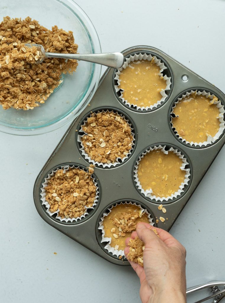 putting streusel on top of batter in muffin tin. 