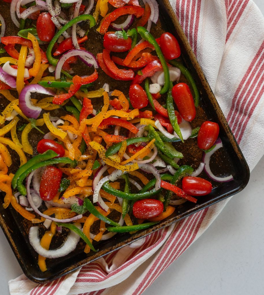 raw vegetables on a baking sheet with a red and white striped towel underneath 