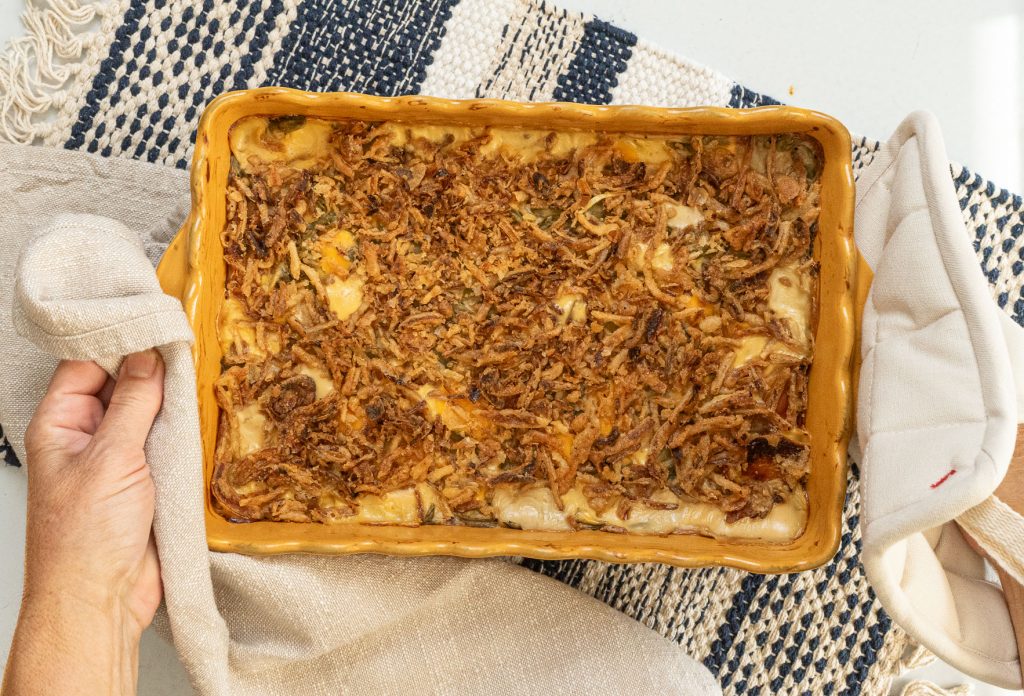 a dish of green bean casserole being set down  on a table