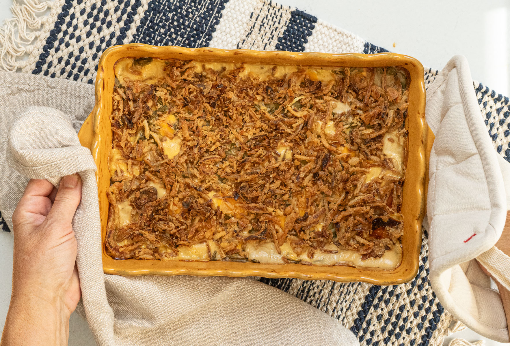 a dish of green bean casserole being set down on a table