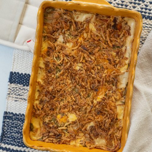 gold dish of green bean casserole on a blue and tan towel