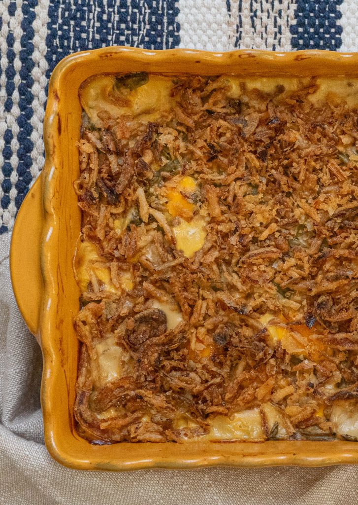 up close photo of casserole dish containing green been casserole bubbling hot and cheesy