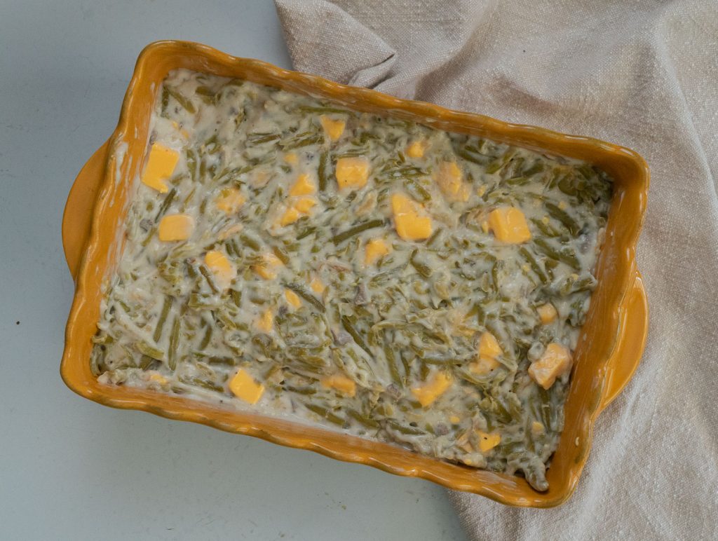 uncooked green bean casserole in a dish on a gray back ground with a tan napkin off to the right side