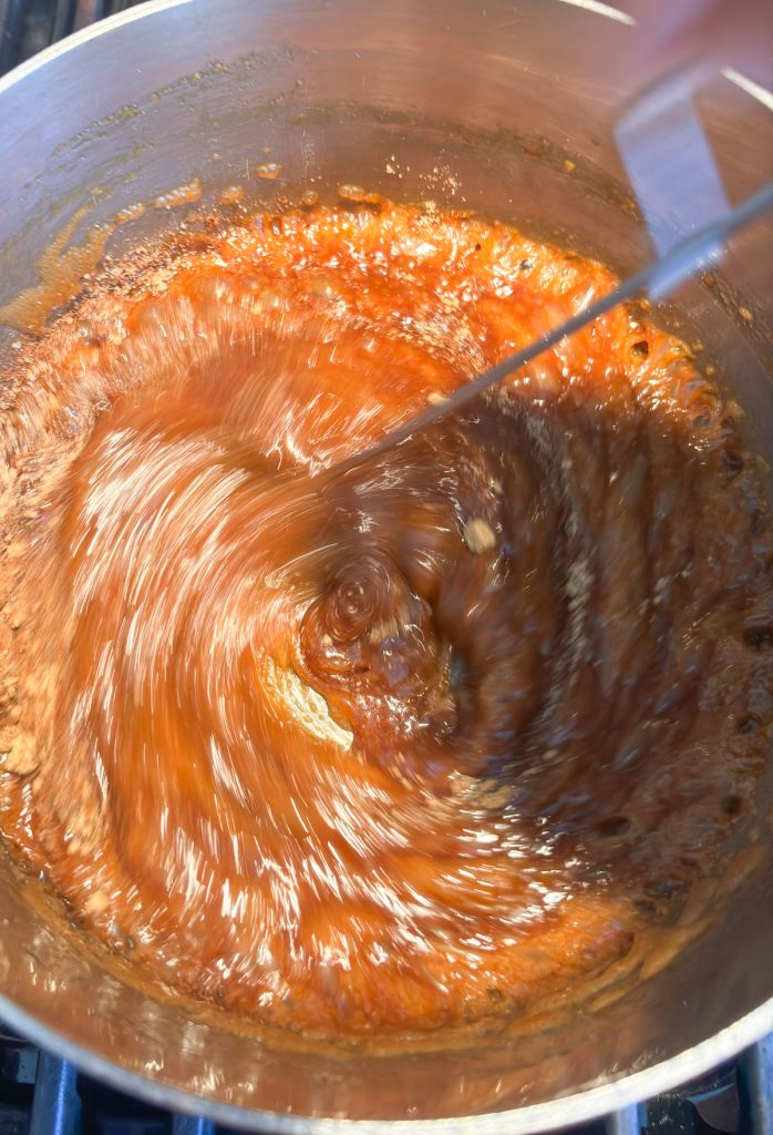 whisking spices into caramel sauce