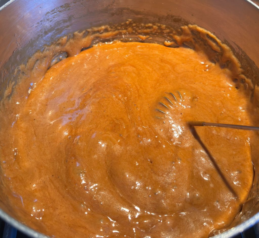 foaming caramel sauce being stirred with a stainless whisk