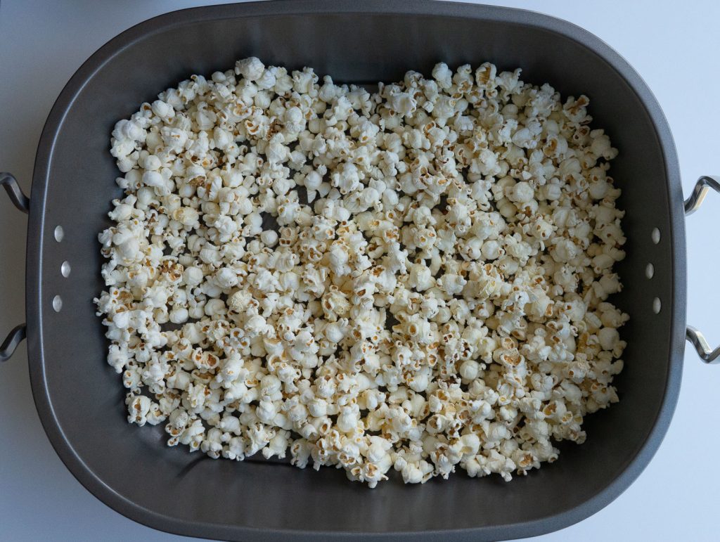 large roasting pan with plain popcorn in an even layer in it