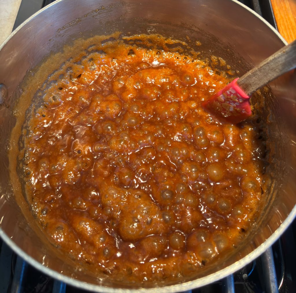 bubbling caramel sauce in a stainless steel sauce pan