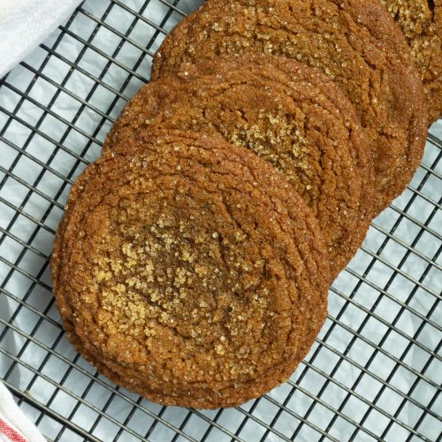 row of molasses cookies cooking on a wire rack on a gray counter top