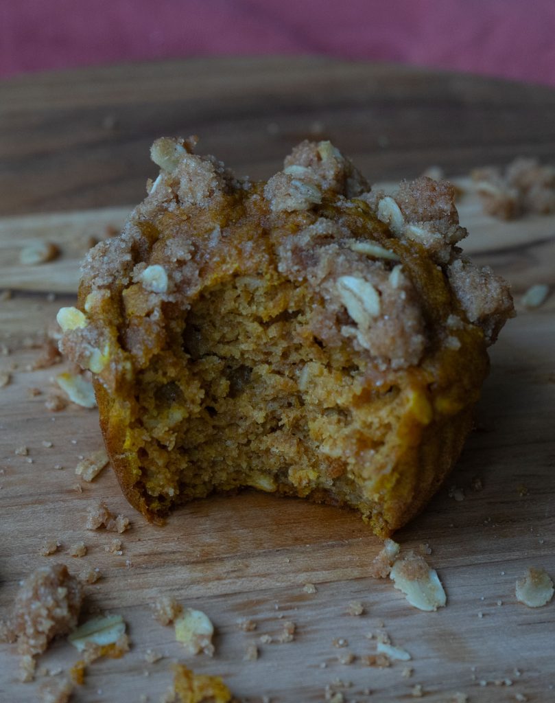 Pumpkin Oatmeal Breakfast Muffin with a bite out of it on a wood cutting board