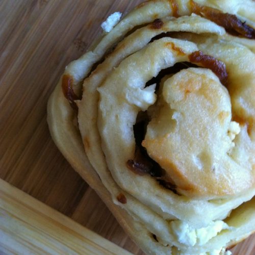 caramelized onion and goat cheese dinner roll on a wood surface