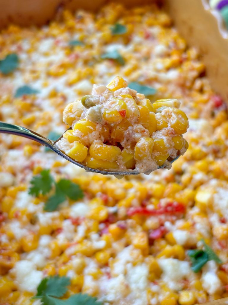 spoon over mexican corn held over the dish full of Mexican corn bake