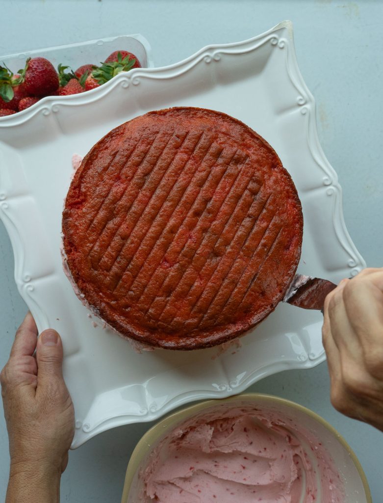 frosting the sides of the strawberry layer cake