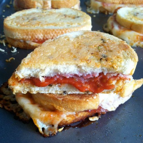 parmesan crusted pizza grilled cheese sandwich stacked on baking sheet