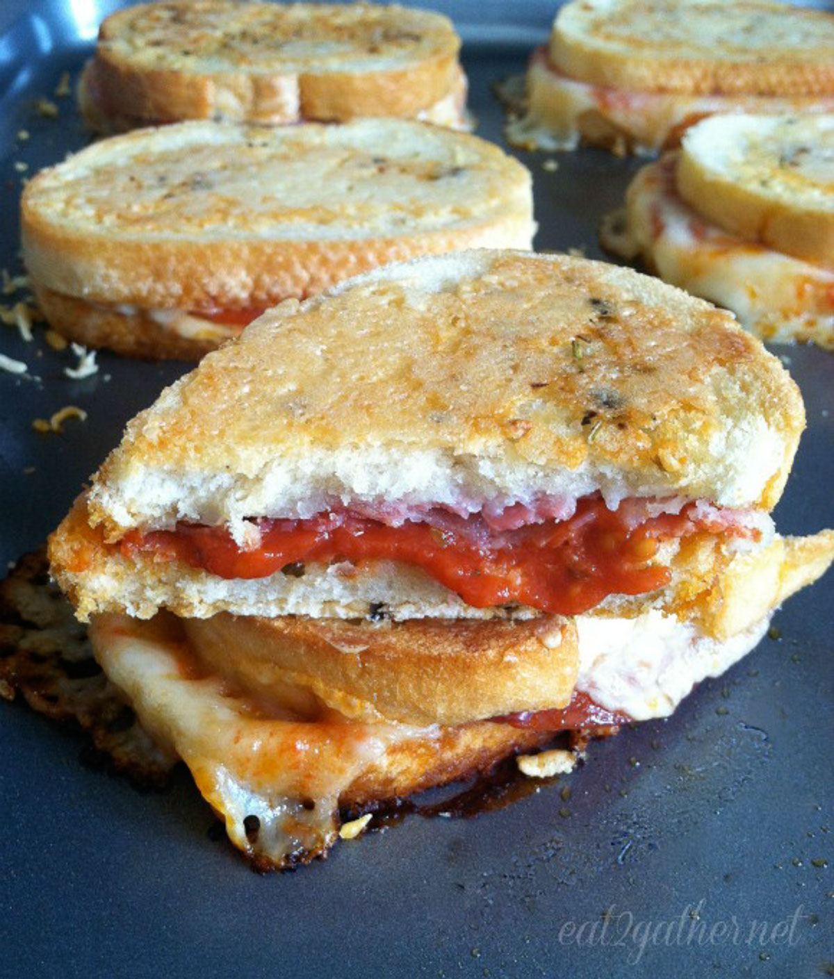 parmesan crusted pizza grilled cheese sandwich stacked on baking sheet