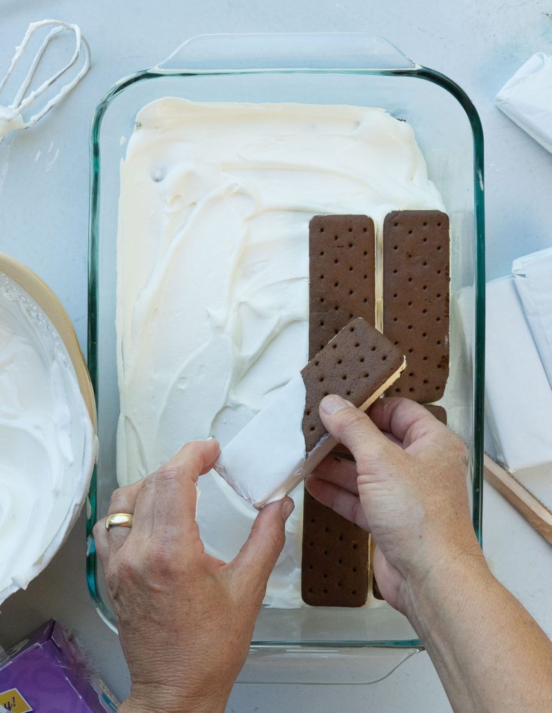 laying second layer of ice cream sandwiches over the whipped cream layer