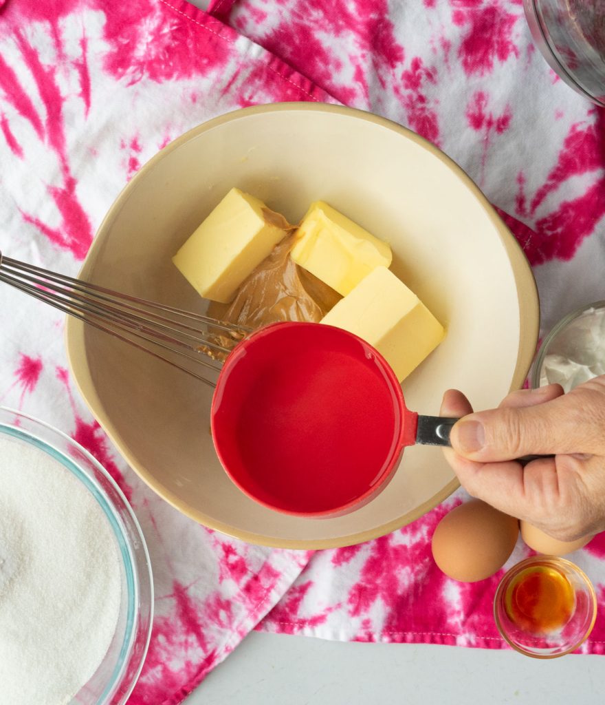 adding boiling water to peanut butter and butter in a bowl