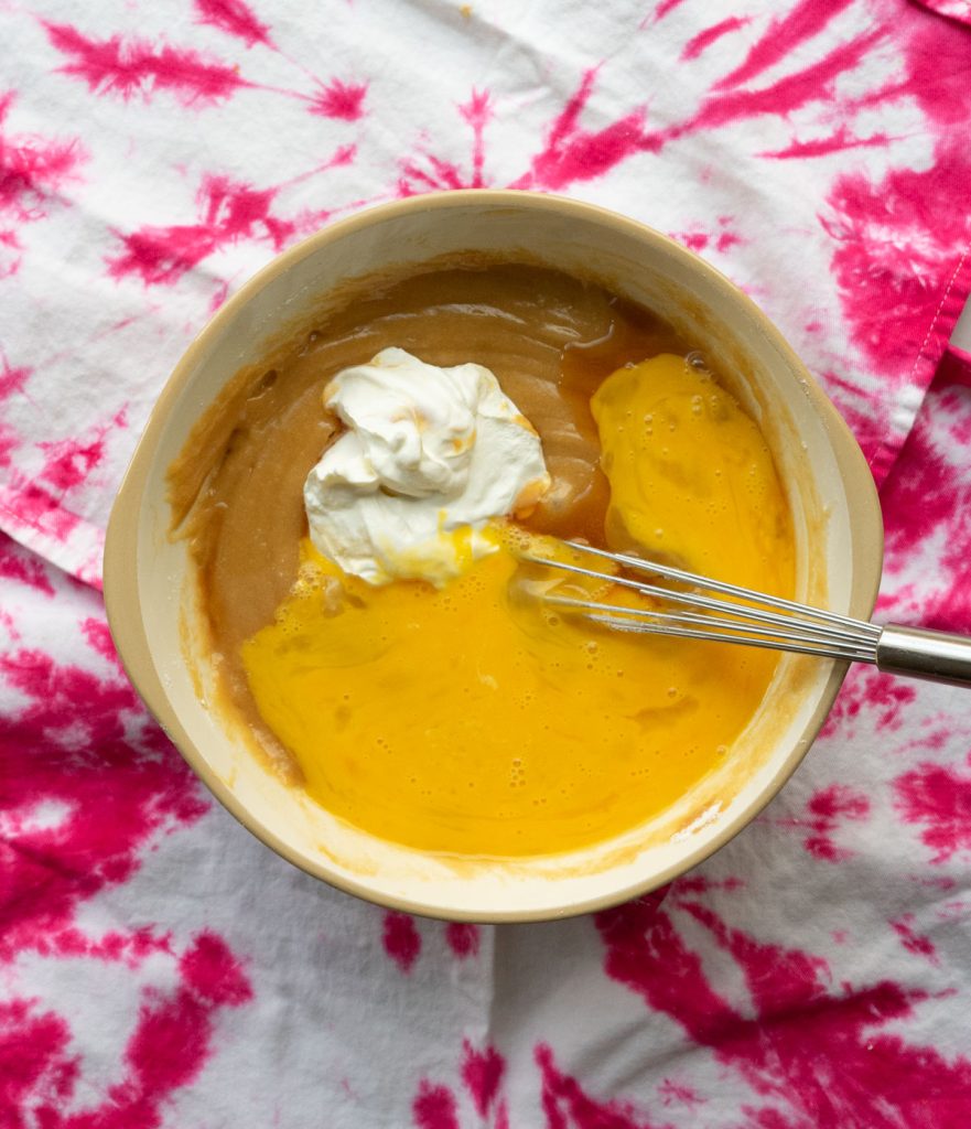 adding sour cream, eggs, and vanilla to the cake batter, combining with a whisk