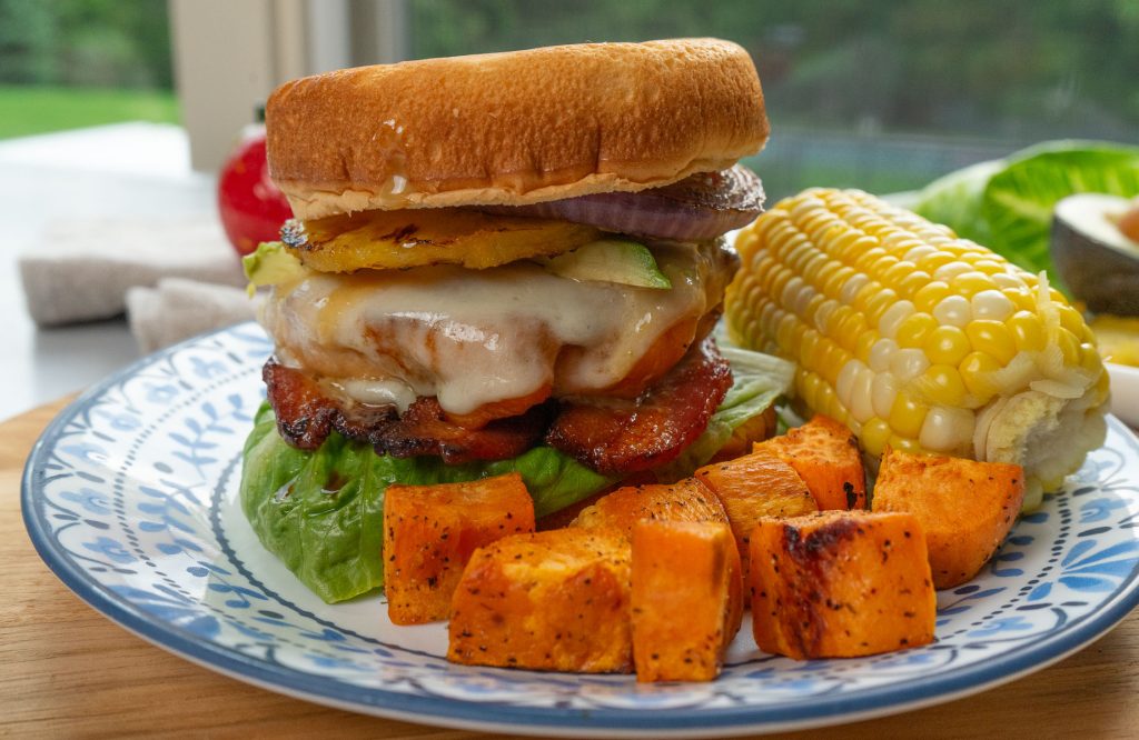 photo of Grilled Pineapple and Chicken Teriyaki Sandwiches with sweet potato and corn on the cob with window looking outside in the background
