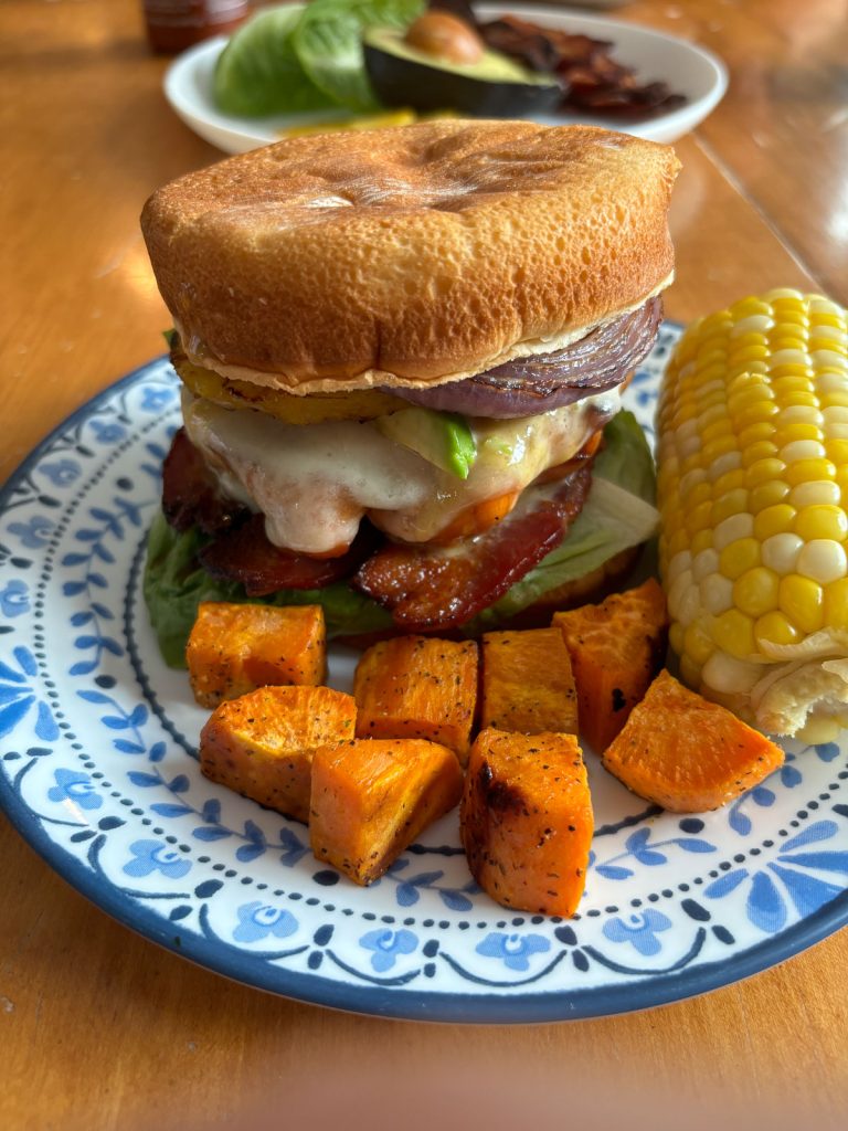 Grilled Pineapple and Chicken Teriyaki Sandwiches on a plate with blue edging with sweet potatoes and corn on the cob