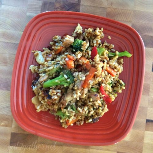 chicken stir-fried rice on a rust colored plate on a butcher block