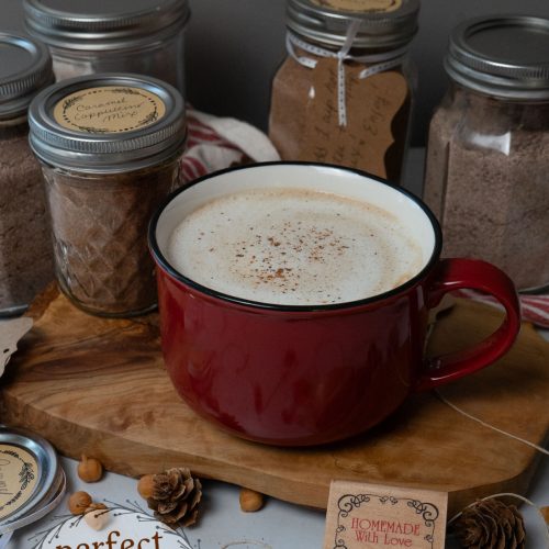 cup of caramel cappuccino sprinkled with nutmeg in a red mug on a wooden board