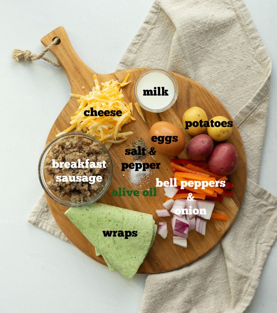 breakfast burrito ingredients on a round wood cutting board wiht a tan napkin underneath