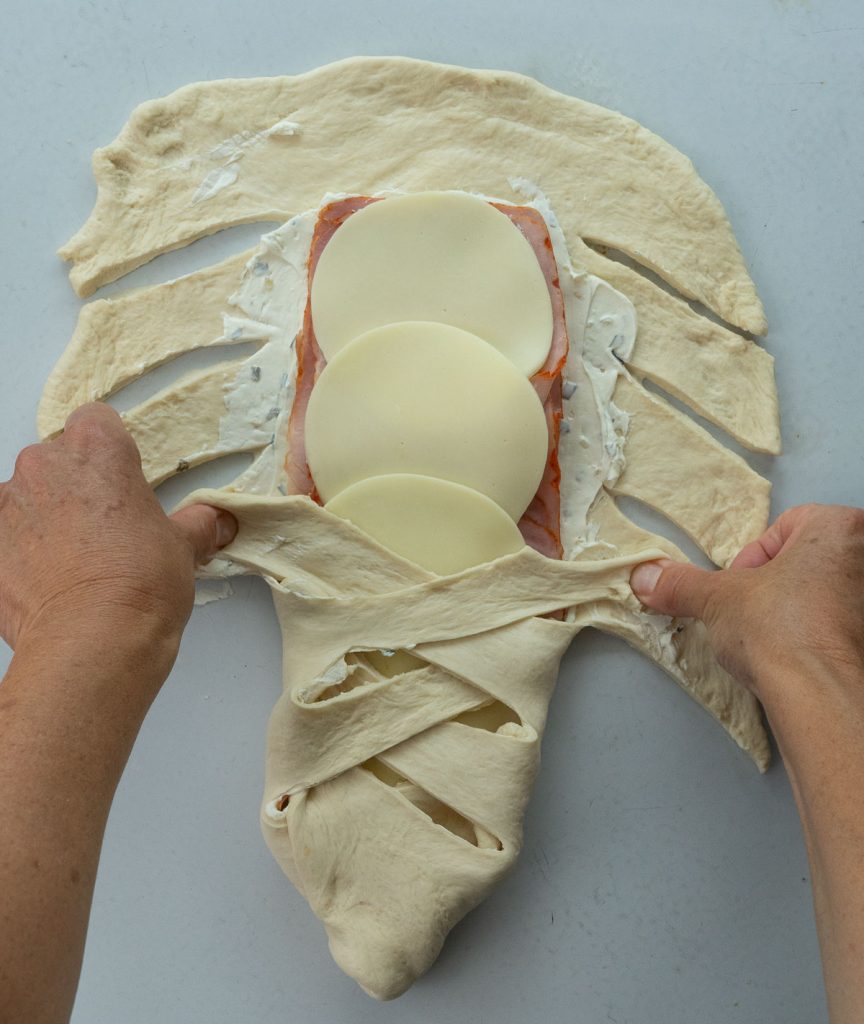 demonstrating how to braid the bread dough around the ham and cheese filling