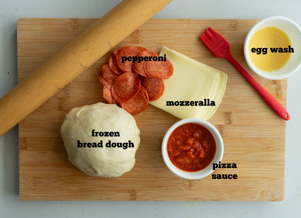 ingredients for baked pizza sandwich on a wood cutting bored 