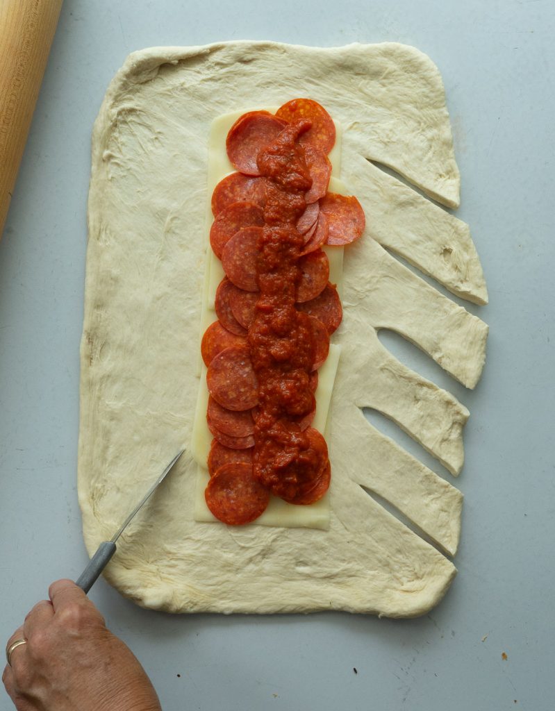 layering the pizza sauce and the pepperoni on top of the cheese layer for baked pizza sandwich