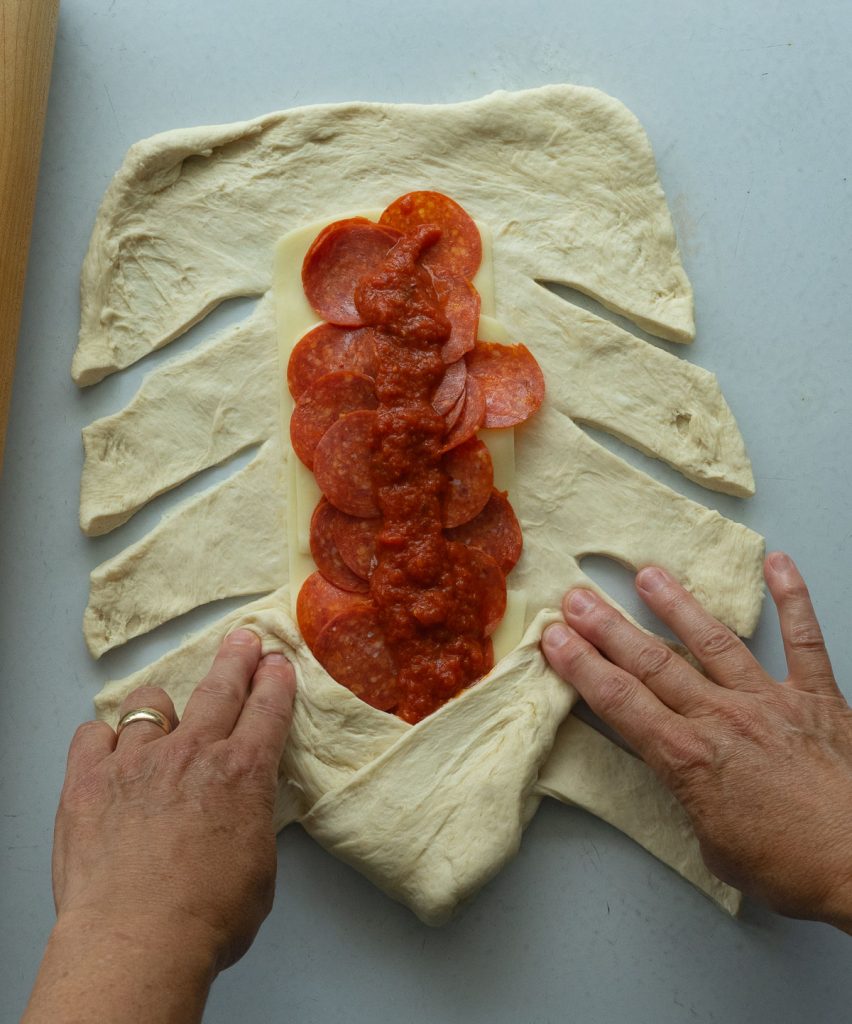 assembly of pizza sandwich braiding the dough around the fillings