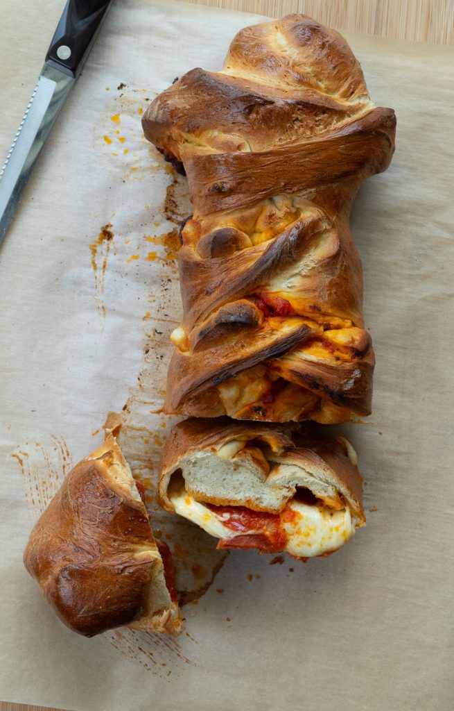 Baked pizza sandwich on a cutting board covered with parchment paper  two slices are cut off 