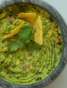 bowl of guacamole garnished with cilantro and tortilla chips